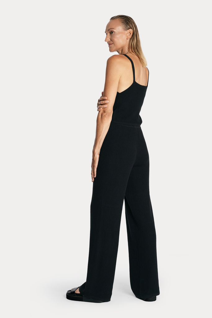 All natural zero waste knitted cotton pants in black with knitted tank top in black color left back side full body view.