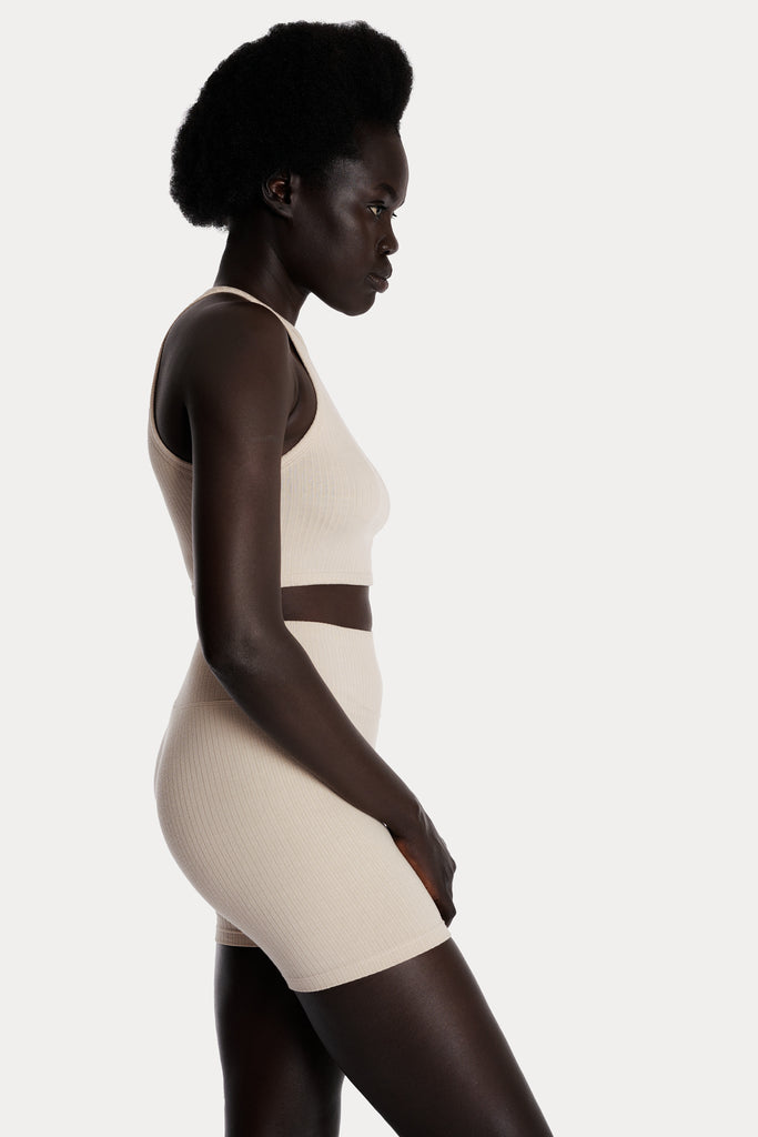 Model wearing sand ribbed biker shorts and a matching sand crop top, right-side close-up view.