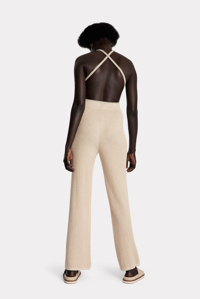 Model wearing a sand ribbed bodysuit and sand knitted cotton pants, full-body back-side.