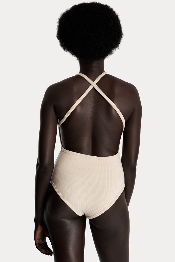 Model wearing a sand ribbed bodysuit back-side closeup.