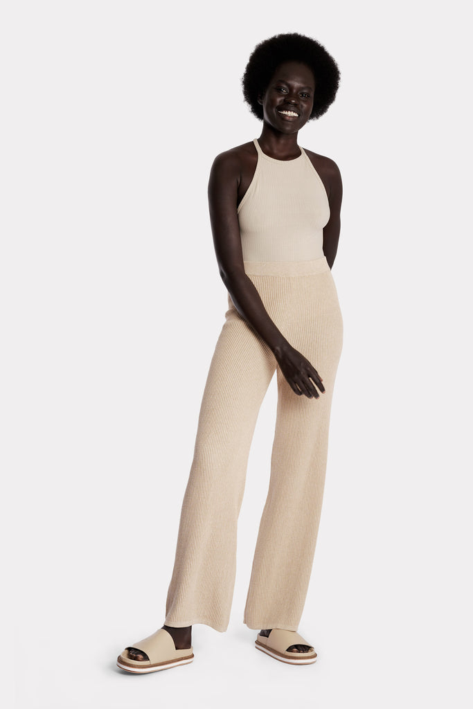 Model wearing a sand ribbed bodysuit and sand knitted cotton pants, full-body front-side view.