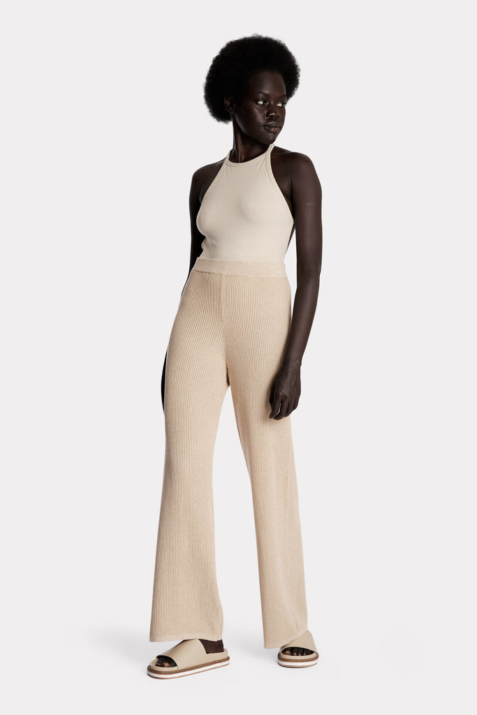 Model wearing a sand ribbed bodysuit and sand knitted cotton pants, full-body front-side view.