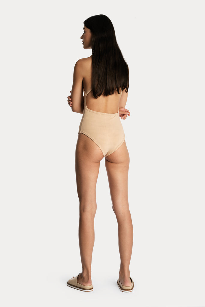 Model wearing a tan ribbed bodysuit, full-body back-side view.