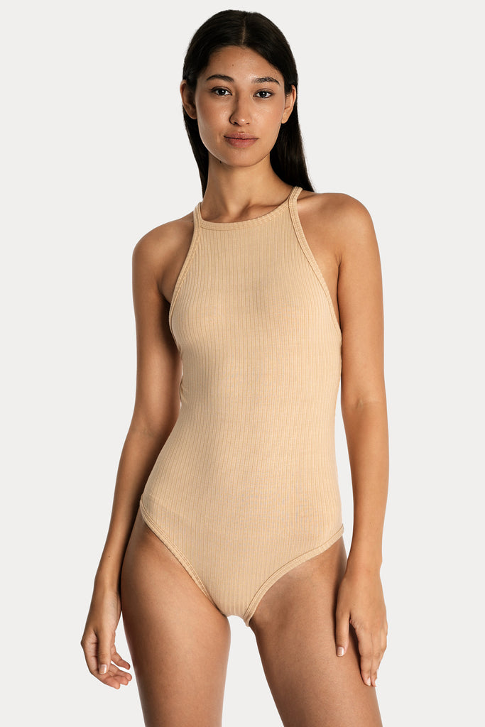 Model wearing a tan ribbed bodysuit, front-side close-up view.