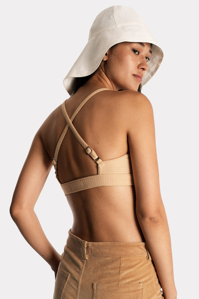 Model wearing a tan ribbed bralette and corduroy trousers, with white linen wide-brim hat, back-right close-up view.