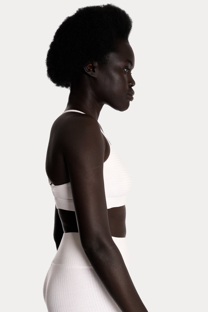 Model wearing a white ribbed bralette and matching white stirrup leggings, right-side close-up.