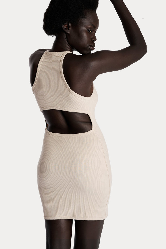 Model wearing a sand ribbed mini dress, back-side closeup view.