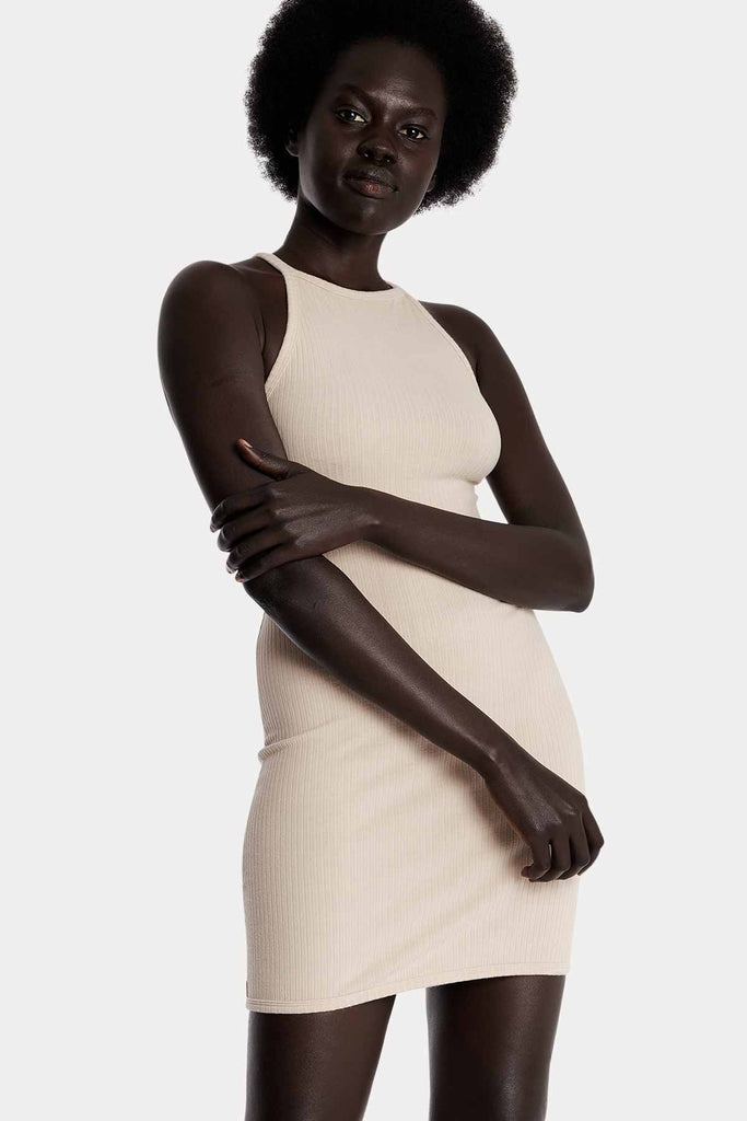 Model wearing a sand ribbed mini dress, front-side close-up view.