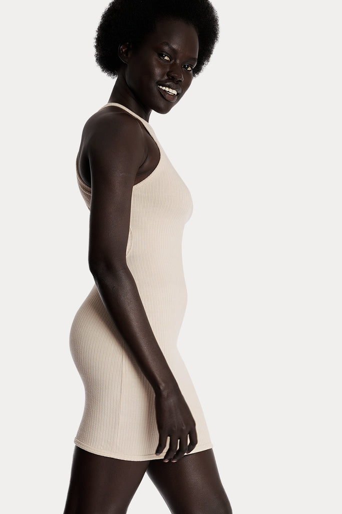 Model wearing a sand ribbed mini dress, right-side close-up view.