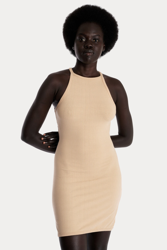 Model wearing a tan ribbed mini dress, front-side close-up view.