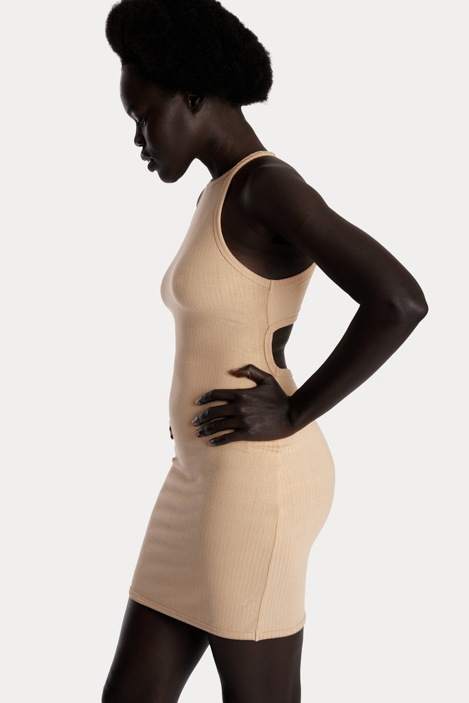 Model wearing a tan ribbed mini dress, left-side close-up view.
