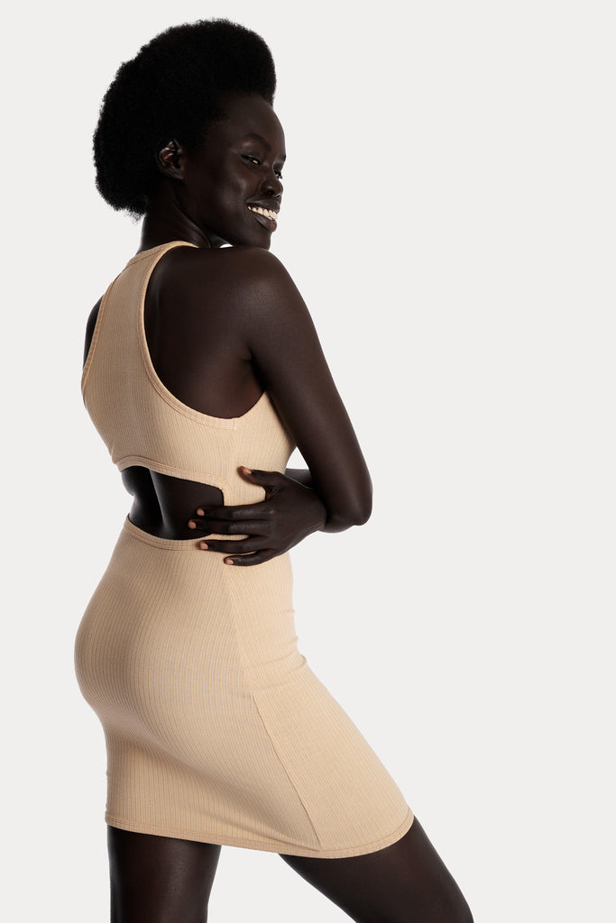 Model wearing a tan ribbed mini dress, right-side close-up view.