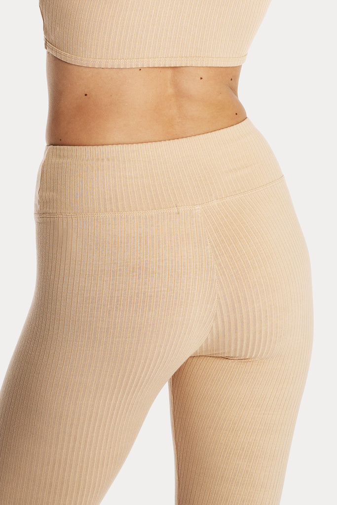 Model wearing tan ribbed stirrup leggings and a matching tan crop top, back-side detail view.
